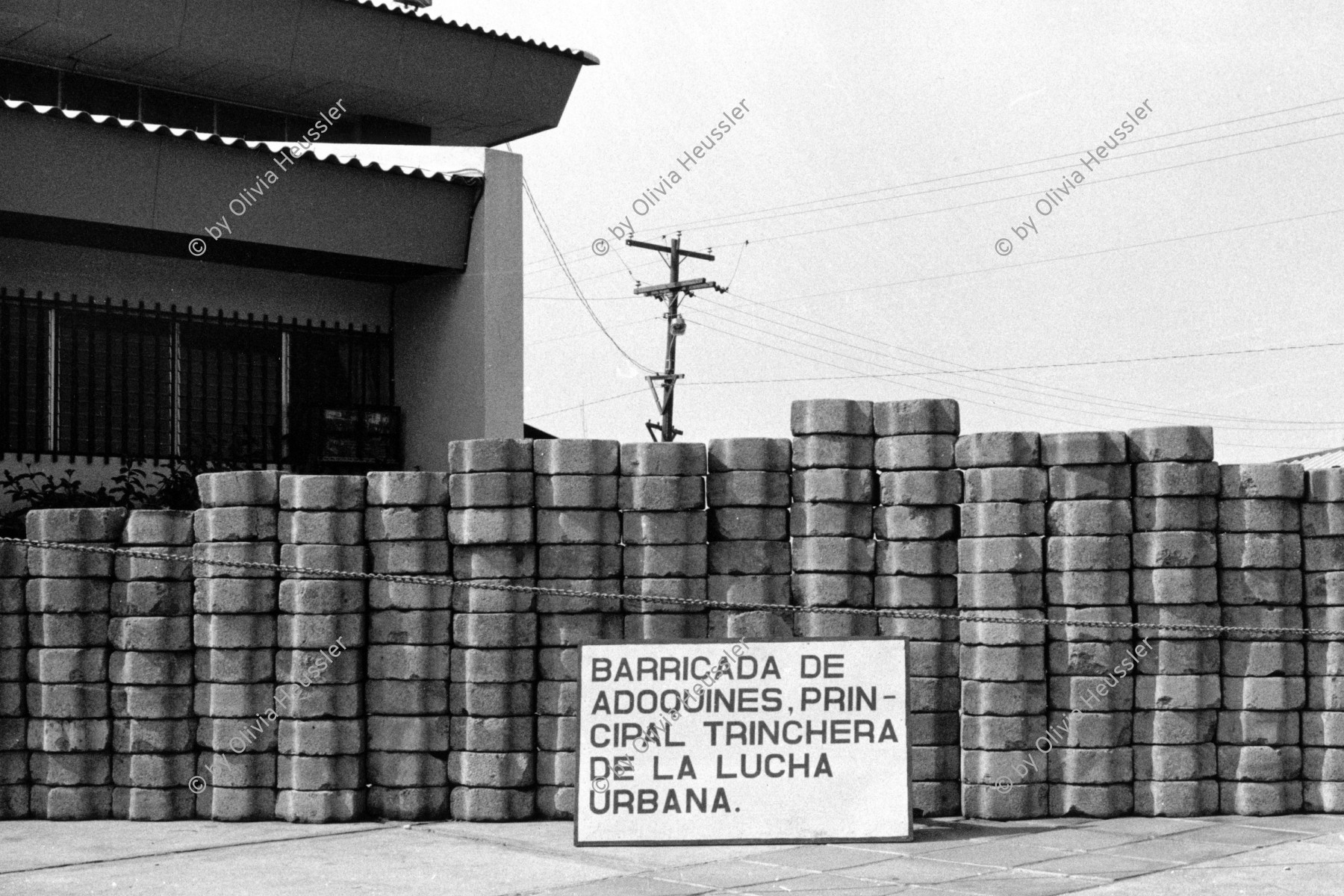 Image of sheet 19840160 photo 8: Barrikade aus Pflastersteine. Revolutions museum Militärmuseum. Managua. Nicaragua 1984 √ america central museo de la revolucion adoquines banner 
 Barricada de adoquines principal trinchera de la lucha urbana.
Barricade cobblestone main urban trench fighting.


© 1984, olivia heussler /www.clic.li
Los adoquines (del árabe ad-dukkân, "piedra escuadrada") son piedras o bloques labrados y de forma rectangular que se utilizan en la construcción de pavimentos. El material más utilizado para su construcción ha sido el granito, por su gran resistencia y facilidad para el tratamiento. Sus dimensiones suelen ser de 20 cm. de largo por 15 cm. de ancho, lo cual facilita la manipulación con una sola mano