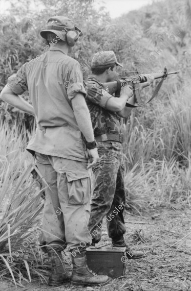 Image of sheet 19840180 photo 6: Im US-Amerikanischen Militär-Ausbildungslager Centro de Entrenamiento Militar (CREM) an der honduranischen Atlantikküste bei El Castillo.Salvadorianische Soldaten. US-Army Soldaten mit M-16 Maschinen gewehre. 
The M16 rifle, officially designated Rifle, Caliber 5.56 mm, M16, is the United States military version of the AR-15 rifle.
Helikopter Flugzeug Ausbildung im Schiessen mit amerikanischem Instruktor. US-Army Soldaten in Zivil vor Bar. Junge schleckt US Marmelade aus Dose. Honduranische Polizei. Anit Kommunisten Wandmalerei. Spray Wachturm in Palmerola. Junge und Soldaten. Bahnhof Eisenbahn. Mädchen und Mutter auf dem Weg zur Kirche mit Mais blätter. Lacayo ehem. Nic. Kulturminister und Mann von Anna Qriquillon. Gabriela Battaglia. San Pedro Sula Honduras Mittelamerika Centralamerica 1984