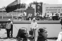 Image of sheet 19840290 photo 21: Geburtstag Sandinos. Des Generals des freien Menschen, wird gefeiert. «Sandino vive» steht an den Mauern. Kinder in Reihe. Gruppenbild. Bühne. FSLN Fahne. Mann Soldat mit Maske. Kommandanten mit Strohhüten. Fahnen. Mascottchen kleines Kind in Uniform. Marimbas werden an der Demo für Sandino mitgetragen. Masken werden getragen. Mural Wandmalerei Ein junger Soldat der den Helikopter abgeschossen hat mit den Honduranern drin. Nicaragua 1984