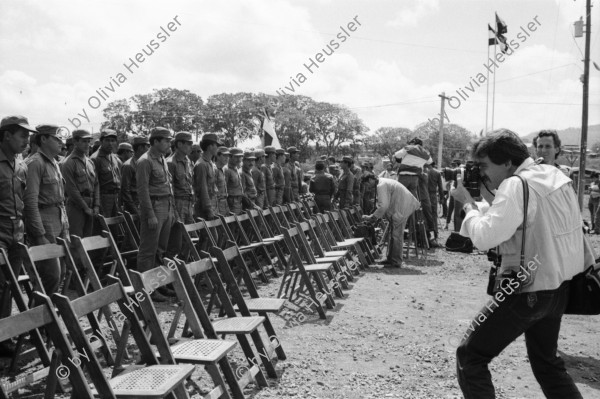 Image of sheet 19840330 photo 28: Luis Enrique Mejia Godoy  in Managua. Kommandant Comandante Tomas Borge unter dem Abbild von Carlos Fonseca. Soldaten Bill Gentil fotografiert leere Stühle und Soldaten. alter Soldat und Sandinist. Junge Sandinistinnen und Mütter gefallener Soldaten protestieren Protest Amerikanische Journalistin Cookie Hood und Soldaten.
1984 Nicaragua