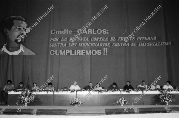 Image of sheet 19840330 photo 4: Luis Enrique Mejia Godoy  in Managua. Kommandant Comandante Tomas Borge unter dem Abbild von Carlos Fonseca. Soldaten Bill Gentil fotografiert leere Stühle und Soldaten. alter Soldat und Sandinist. Junge Sandinistinnen und Mütter gefallener Soldaten protestieren Protest Amerikanische Journalistin Cookie Hood und Soldaten.
1984 Nicaragua