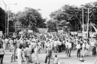 Image of sheet 19840410 photo 21: Viele Nordamerikaner Innen demonstrieren vor ihrer Botschaft. Protest US Amerikaner innen. U.S.A. Portrai Frau mit hut. Die Fahne weht auch stolz über ihr. Peace means stoping US backed Invasion of Nicaragua. Marsch am 19.Juli auf der Carretera Norte, vorbei an den Texnicsa. Wandbild mit Sandino.