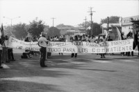 Image of sheet 19840410 photo 41: Viele Nordamerikaner Innen demonstrieren vor ihrer Botschaft. Protest US Amerikaner innen. U.S.A. Portrai Frau mit hut. Die Fahne weht auch stolz über ihr. Peace means stoping US backed Invasion of Nicaragua. Marsch am 19.Juli auf der Carretera Norte, vorbei an den Texnicsa. Wandbild mit Sandino.