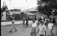 Image of sheet 19840410 photo 47: Viele Nordamerikaner Innen demonstrieren vor ihrer Botschaft. Protest US Amerikaner innen. U.S.A. Portrai Frau mit hut. Die Fahne weht auch stolz über ihr. Peace means stoping US backed Invasion of Nicaragua. Marsch am 19.Juli auf der Carretera Norte, vorbei an den Texnicsa. Wandbild mit Sandino.