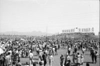 Image of sheet 19840420 photo 15: Todo para los frente de Guerra. Todo para los Combatientes. Am 5. Jahrestag der Revolution festen auch die Fabriken an der Carretera Norte. Fabrikarbeiter. Sicht durch die Ruinen aufs Gebäude der Banco de America. Im Vordergrund Demonstration. Die Fahnen wehen für die Revolution auf dem Platz. Das Nic. Rote Kreuz verteilt den erhitzten Köpfen Trinkwasser. Erdbebenruinen. Managua 1984