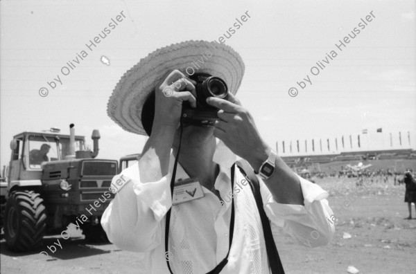 Image of sheet 19840440 photo 28: Ein Jongleur und ZuschauerInnen Plakat 'Somos la Esperanza de America'. Wir sind die Hoffnung Amerika's. Panzer. Oscar Cantarero Ortegas Hoffotograf Fotograf mit Strohhut. Gruppenbild Demonstration für den zurückkehrenden Arturo Cruz im Flughafen von Managua. Helikopter. Essstand mit Schweinefettstücken. Managua 1984