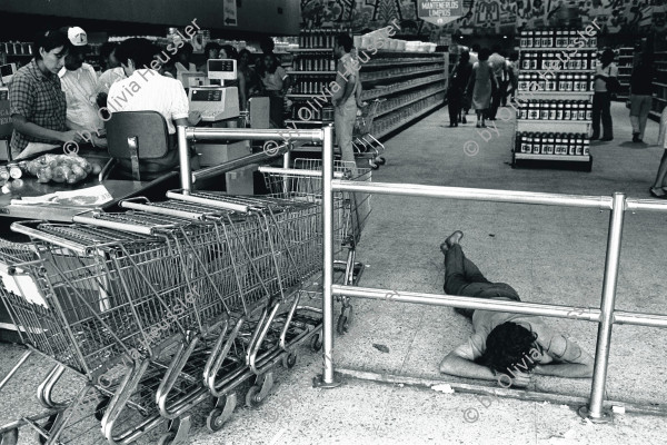 Image of sheet 19840480 photo 19: Ein arbeitsloser und betrunkener Desperado hält im Supermarkt «La Colonia» Plaza España, seine Siesta. Er schläft am Boden. Managua Nicaragua 1984 √ Schlafender Super markt market Einkaufszentrum Shop 
Unemployed desperado sleeps in supermarket 'La Coloñia'. super mercado mann schläft man sleeping
Out of: Der Traum von Solentiname The dream of Solentiname / El sueño de Solentiname page 51 
Out of: From time to time  / Von Zeit zu Zeit

Siesta at al Colonia supermarket, with mural by artist Leoncio Saenz in the background. 
Exhibition

gerahmt framed passepartout 37 x 52 cm