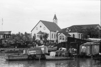 Image of sheet 19840500 photo 3: Majorettes treten für Daniel Ortega auf. Kindergruppe. Kirche von Bluefields. Esso Tankstelle. kleine Fischerboote im Hafen von B-. Palmen. Kinder vor Wandmalerei. Mascotta. kleines Mädchen als Kindersoldat verkleidet. S.M.P. Servicio Militar Patriotico. Tafel des P.L.I. in Managua. Partido Liberal Independiente. Atlantikküste RAAS 1984