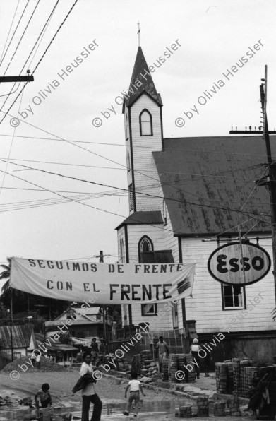 Image of sheet 19840500 photo 5: Majorettes treten für Daniel Ortega auf. Kindergruppe. Kirche von Bluefields. Esso Tankstelle. kleine Fischerboote im Hafen von B-. Palmen. Kinder vor Wandmalerei. Mascotta. kleines Mädchen als Kindersoldat verkleidet. S.M.P. Servicio Militar Patriotico. Tafel des P.L.I. in Managua. Partido Liberal Independiente. Atlantikküste RAAS 1984