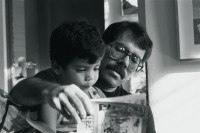 Image of sheet 19840530 photo 30: Out of: Der Traum von Solentiname  /  The dream of Solentiname  /  El sueño de Solentiname page 65
Daniel Ortega en casa leyendo un cómic con su hijo. Managua, 1984.