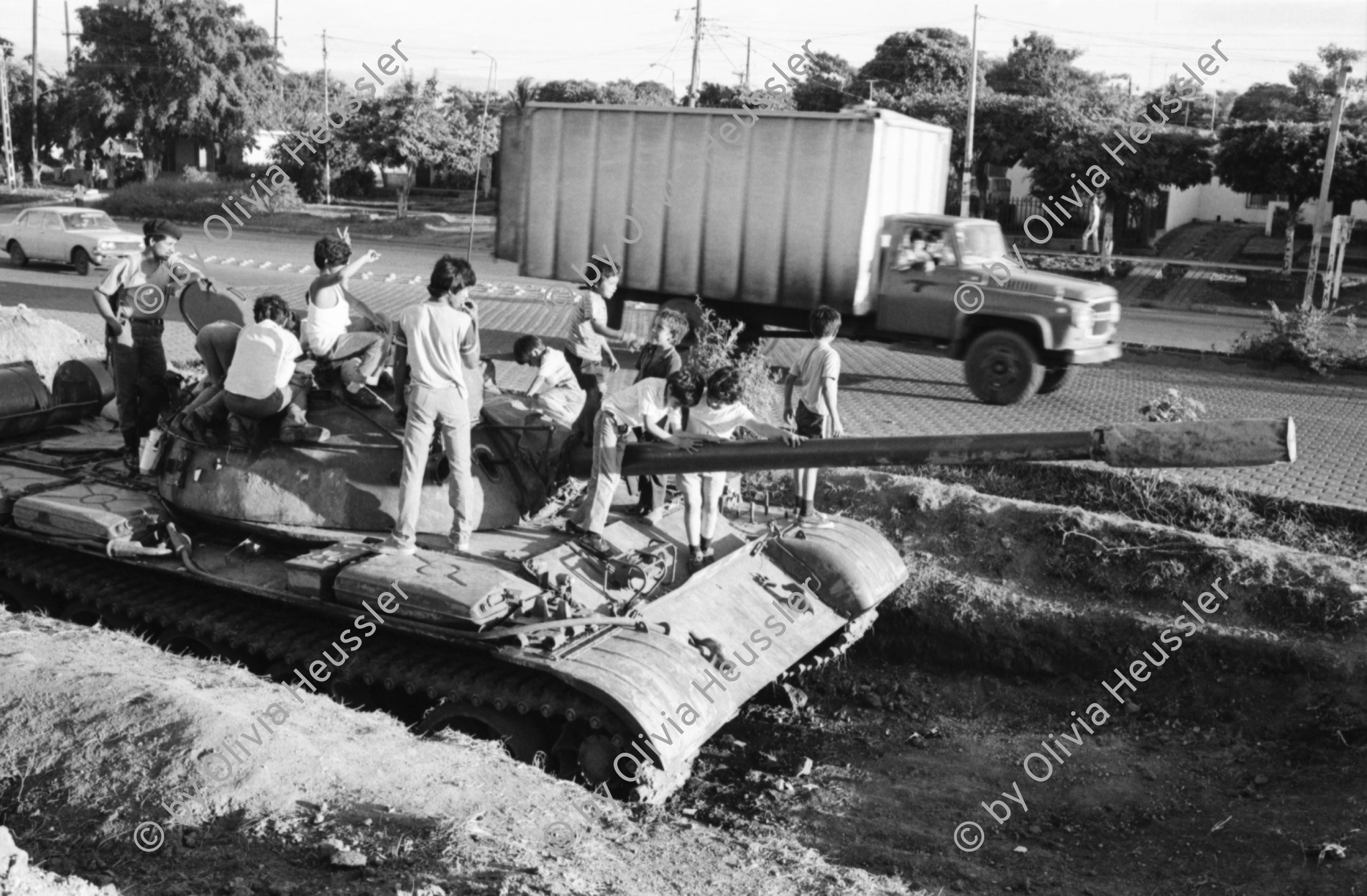 Image of sheet 19840660 photo 26: russische sovietische Tanks Panzer EPS stehen um Managua herum. Invasionsangst Kind mit Taube steht vor Panzer. Gewehre gegen den Himmel gerichtet. Panzer ist mit Pflanzen getarnt. Mann fotografiert sein Kollege auf Panzer stehend. Mann fotografiert. Managua Nicaragua 1984