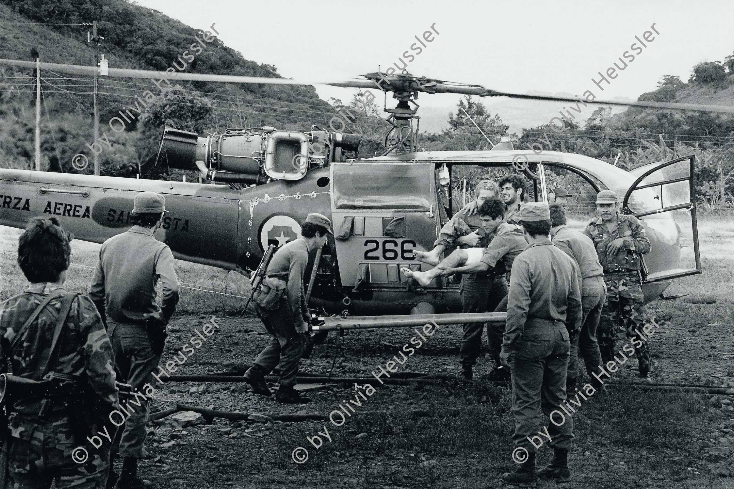 Image of sheet 19840690 photo 13: Der verwundete Copilot der Aluette, nach einer Contraattacke in Bocay, wird ins Militärspital von Apanas gebracht. Jinotega Nicaragua 1984 √
Militär Armee sandinisten Soldaten
Army soldier wounded Helikopter Helicopter Pilot military sandinist aircraft  hospital
Aus: Out of: Der Traum von Solentiname / The dream of Solentiname / El sueño de Solentiname page 81

Bajando a un herido de un helicóptero
Base militar de Apanás, Dpto. de Jinotega, 

The Sandinista Popular Army (or People's Army; Ejército Popular Sandinista, EPS) was the military established in 1979 by the new Sandinista government to replace the National Guard, following the overthow of Anastasio Somoza Debayle.