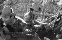 Image of sheet 19840690 photo 16: Flugaufnahme aus Helikopter. Soldatin kocht unter Zeltplane. Verwundete Soldaten des Ejercito Popular Sandinista EPS nach einem Angriff der Contrarebellen der FDN, spielen Schach. und lesen im Bett. Verwundeter wird aus Helikopter geladen. Es ist der Pilot des anderen Helis. Alouette, Die Aluette ist noch aus Beständen des Somoza-Clans. Die Sandinisten kannten dieses Fluggerät nicht und haben uns prompt auf dem Flug nach San José de Bocay beschossen.
Wir konnten aber ohne Probleme landen. Soldaten spielen Musik. Ausgediente Soldatenstiefel liegen am Boden auf einem Haufen. Ein junger Soldat isst seine Eierspeise elegant auf Tortilla und seinem Hut als Tisch. Die Tortilla dient als Teller. So verbrennt er seine Finger nicht. 
Nicaragua Apanas Jinotega 1984
Pop-Gruppe in Managua. Musikgruppe Igni Tawanka Olivia Portrait im TV-Monitor.