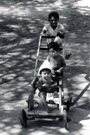 Image of sheet 19850030 photo 37: Der ältere Bruder spaziert seine kleinen Geschwister im selbstgebauten Kinderwagen. Chinandega Nicaragua 1985 √ Kinder Niños selfmade car