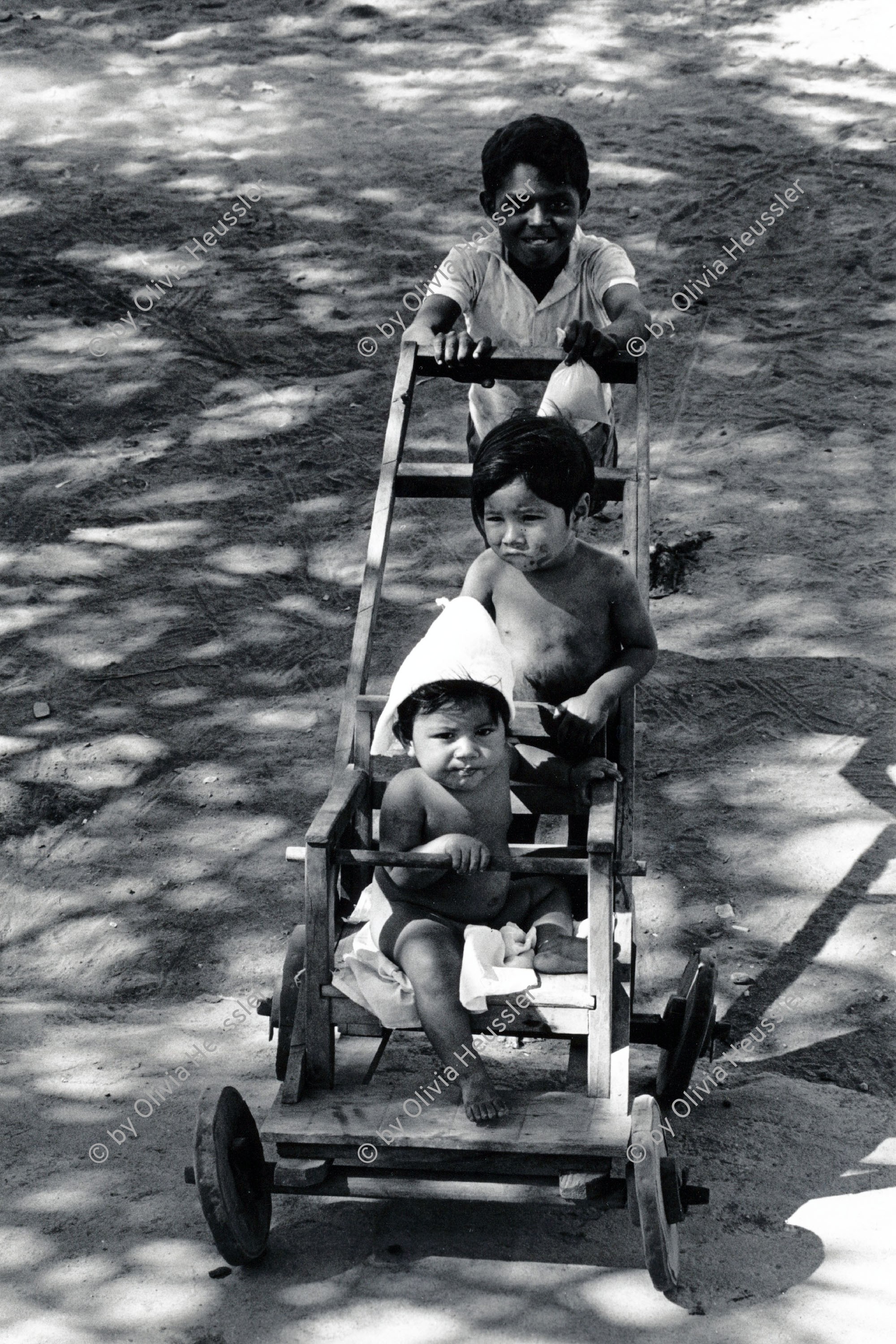 Image of sheet 19850030 photo 37: Der ältere Bruder spaziert seine kleinen Geschwister im selbstgebauten Kinderwagen. Chinandega Nicaragua 1985 √ Kinder Niños selfmade car