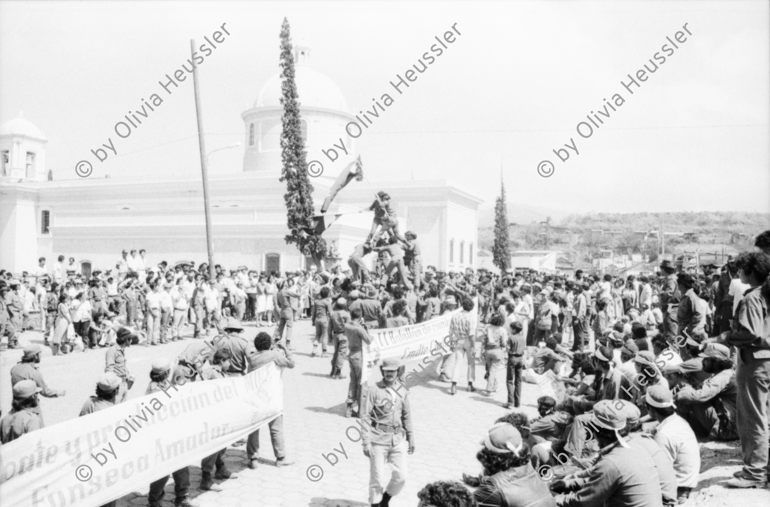 Image of sheet 19850120 photo 23: Gruppenbild der Kaffeebrigade. Abschied. Nica. Kameramann, Internationalistinnen Kaffeepflücker Brigade. Sängerin. sandinist Cmdte. Kommandant der Revolution Daniel Ortega spricht. im Hintergrund liegt Matagalpa. Kaffeesäcke. 
Product of Nicaragua libre. Lavado Segovia. Kaffee Nicaragua 1985 Arbeit Norma Elena Gadea singt.