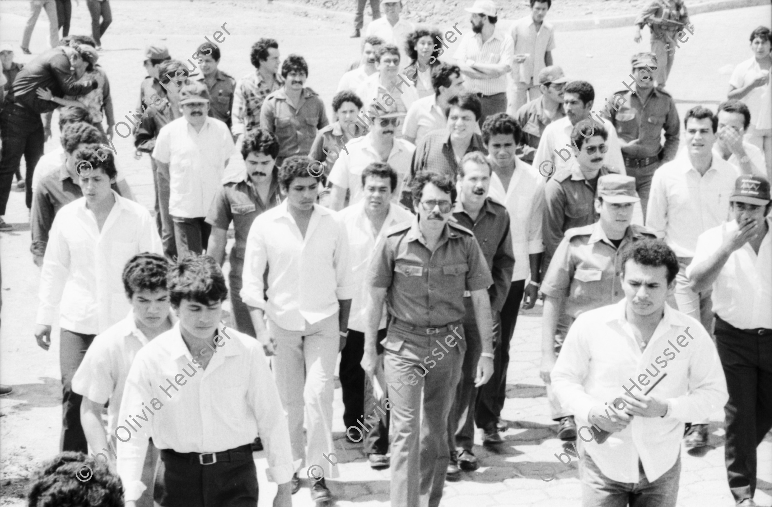 Image of sheet 19850120 photo 25: Gruppenbild der Kaffeebrigade. Abschied. Nica. Kameramann, Internationalistinnen Kaffeepflücker Brigade. Sängerin. sandinist Cmdte. Kommandant der Revolution Daniel Ortega spricht. im Hintergrund liegt Matagalpa. Kaffeesäcke. 
Product of Nicaragua libre. Lavado Segovia. Kaffee Nicaragua 1985 Arbeit Norma Elena Gadea singt.