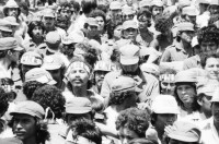 Image of sheet 19850120 photo 27: Gruppenbild der Kaffeebrigade. Abschied. Nica. Kameramann, Internationalistinnen Kaffeepflücker Brigade. Sängerin. sandinist Cmdte. Kommandant der Revolution Daniel Ortega spricht. im Hintergrund liegt Matagalpa. Kaffeesäcke. 
Product of Nicaragua libre. Lavado Segovia. Kaffee Nicaragua 1985 Arbeit Norma Elena Gadea singt.