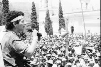 Image of sheet 19850120 photo 33: Gruppenbild der Kaffeebrigade. Abschied. Nica. Kameramann, Internationalistinnen Kaffeepflücker Brigade. Sängerin. sandinist Cmdte. Kommandant der Revolution Daniel Ortega spricht. im Hintergrund liegt Matagalpa. Kaffeesäcke. 
Product of Nicaragua libre. Lavado Segovia. Kaffee Nicaragua 1985 Arbeit Norma Elena Gadea singt.