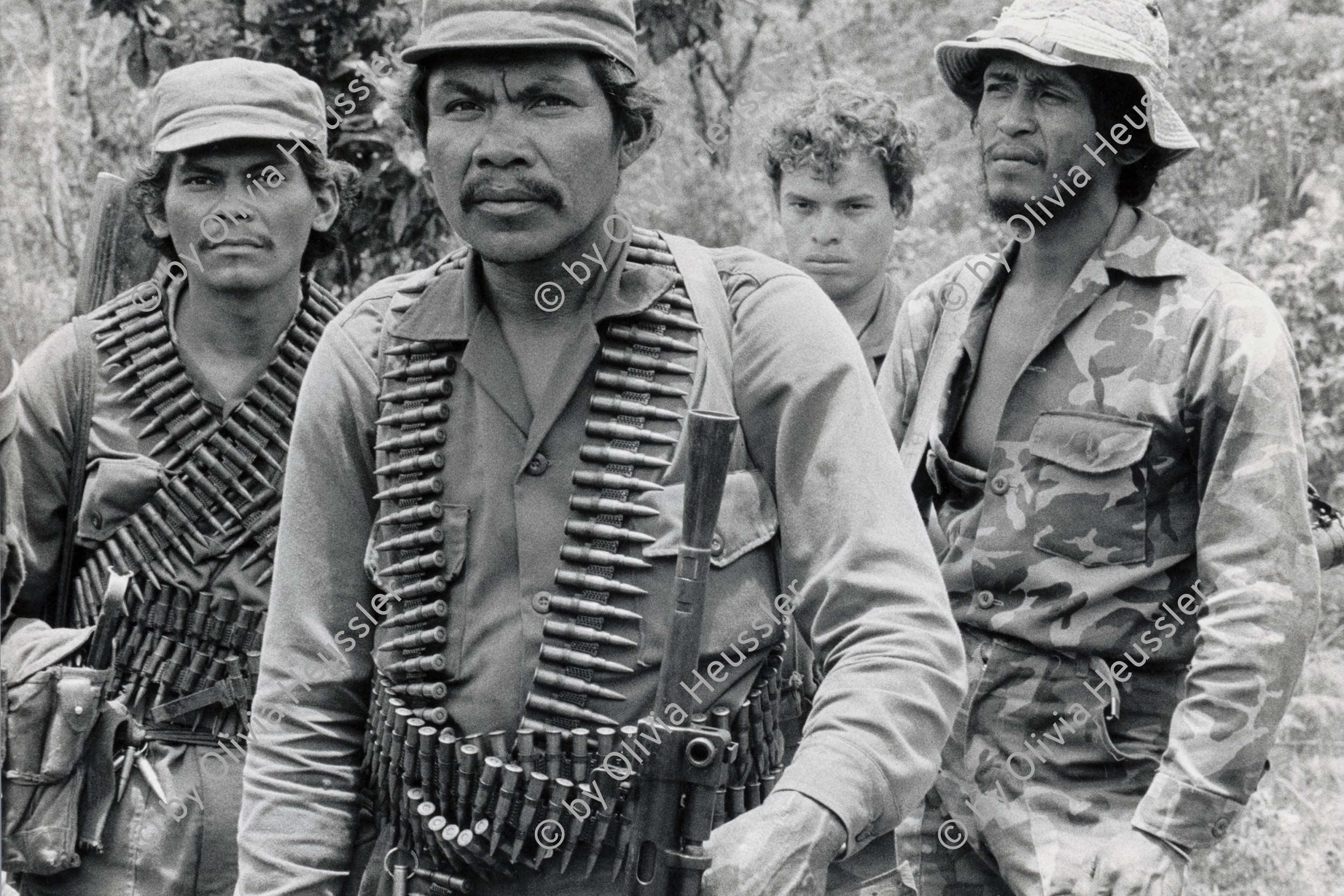 Image of sheet 19850160 photo 24: Männer an der Front Soldat mit Munition Maschinengewehr Gurt um den Körper. Gruppenbild  Cerro 1300. Nicaragua 1985 √ Army Armee EPS Ejército Popular Sandinista Bataillon Battallion Machine Gun Sandinist soldier Military Militär North front Nueva Segovia 

A machine gun is a fully automatic mounted or portable firearm, usually designed to fire bullets in quick succession from an ammunition belt or magazine, typically at a rate of several hundred rounds per minute.

The Sandinista Popular Army (or People's Army; Ejército Popular Sandinista, EPS) was the military established in 1979 by the new Sandinista government to replace the National Guard, following the overthow of Anastasio Somoza Debayle.