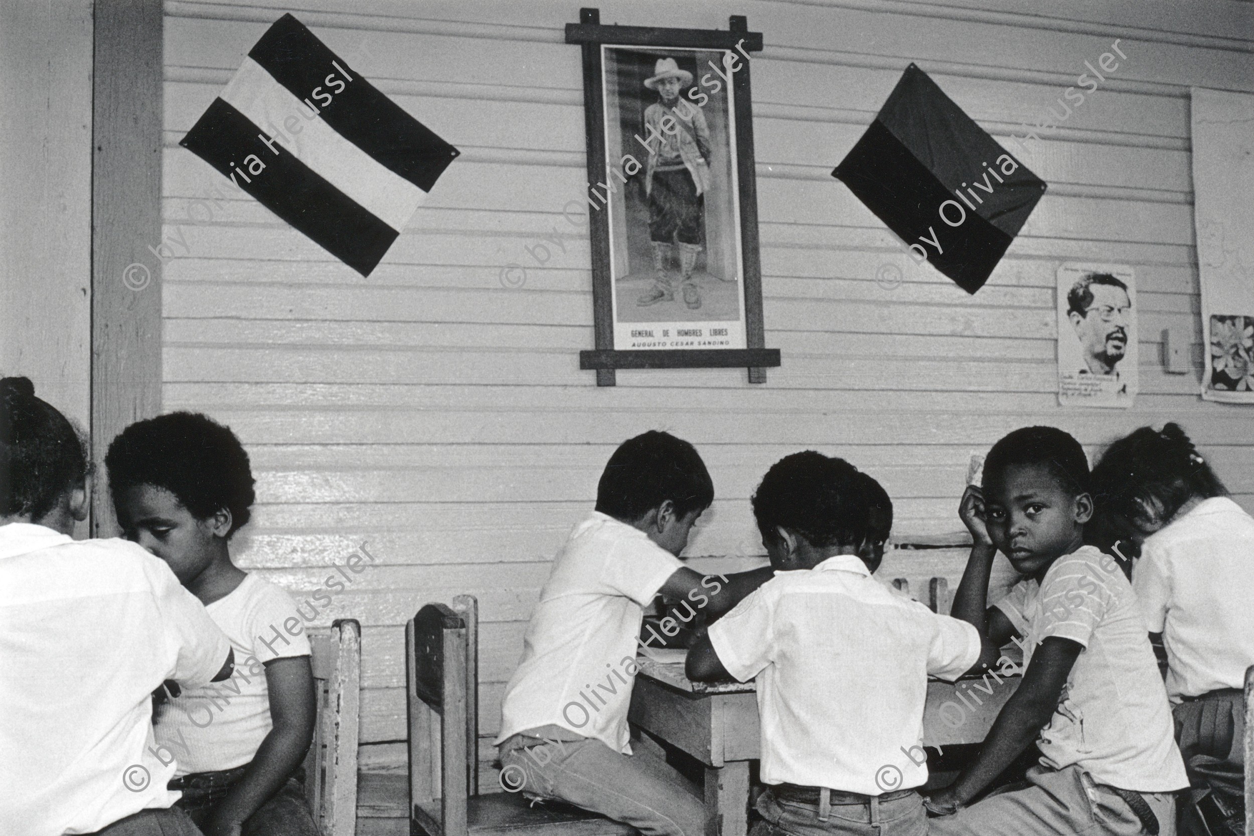 Image of sheet 19850220 photo 30: Miskito Indianer Indigena Die kleinen im Kindergarten werden von einem Poster mit Augusto Cäsar Sandino gut von der Wand herab überwacht. Unterricht im Schreiben. Erste Versuche. RAAS
Nicaragua 1985 √
Bluefields es un municipio de la Región Autónoma del Atlántico Sur, Nicaragua. Su cabecera municipal es Bluefields, que actualmente es sede administrativa del Gobierno Regional Autónoma del Atlántico Sur. Este municipio colinda al norte con el municipio de Kukra Hill, al sur con los municipios de San Juan del Norte y El Castillo, al este con el Mar Caribe y al oeste con los Municipios de Nueva Guinea y El Rama. RAAS 1985
Bluefields (or Blewfields) is the capital of the municipality of the same name, and of Región Autónoma del Atlántico Sur (R.A.A.S.) in Nicaragua. It was also capital of the former Zelaya Department, which was divided into North and South Atlantic Autonomous Regions. It is located on Bluefields Bay at the mouth of the Escondido River.
