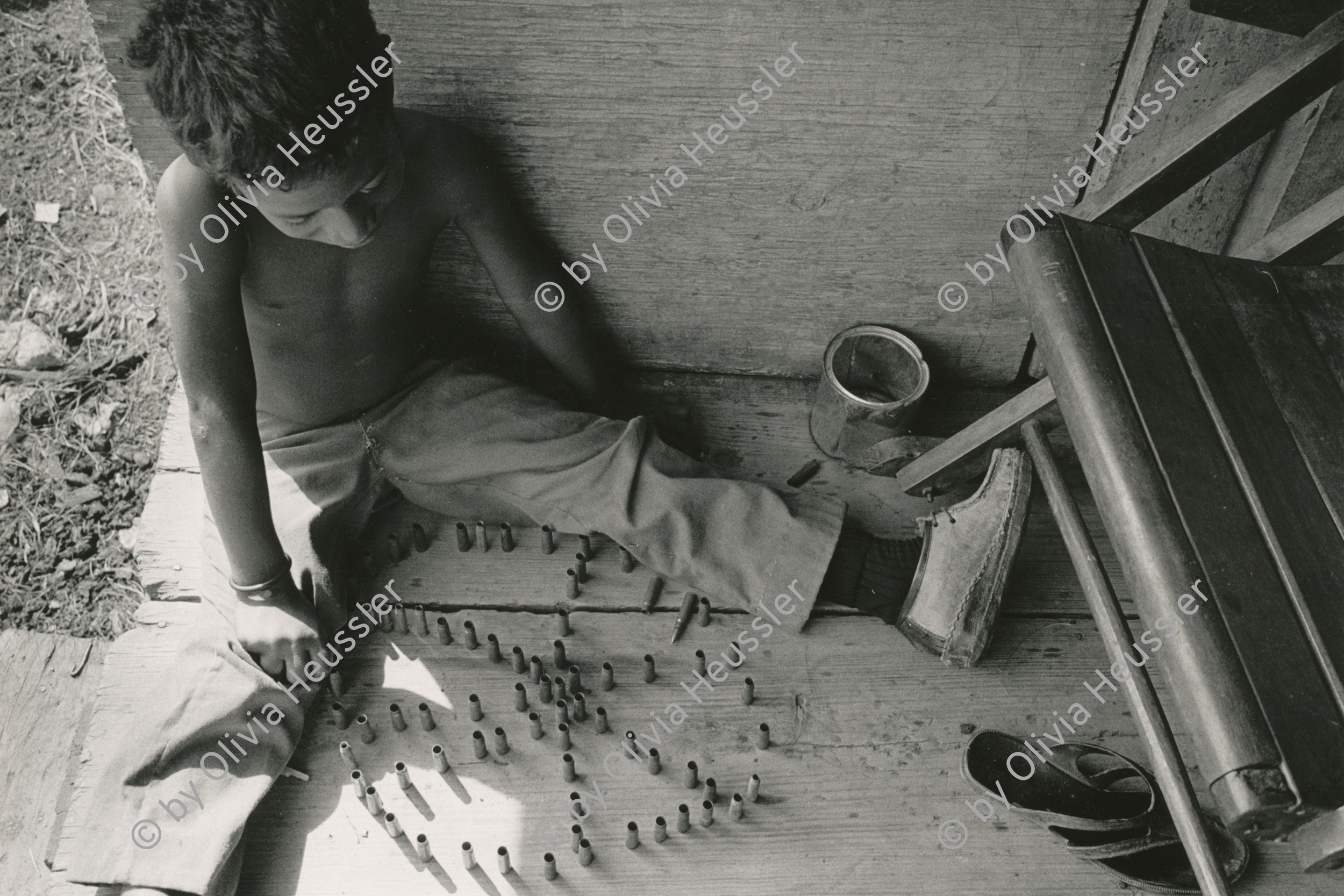 Image of sheet 19850230 photo 5: Knabe Junge Kind spielt mit leeren Patronen hülsen. little boy playes with emty bullets from AK-47.
El Bluff RAAS Nicaragua 1985 √

El Bluff is a port city on the Caribbean coast of Nicaragua within the bay of Bluefields. El Bluff handles limited cargo and has basic piers. It is also a base for the fishing vessels serving the Nicaraguan east coast going out to sea.
War Weapon Krieg Waffen Munition 

© 1985, OLIVIA HEUSSLER / www.clic.li