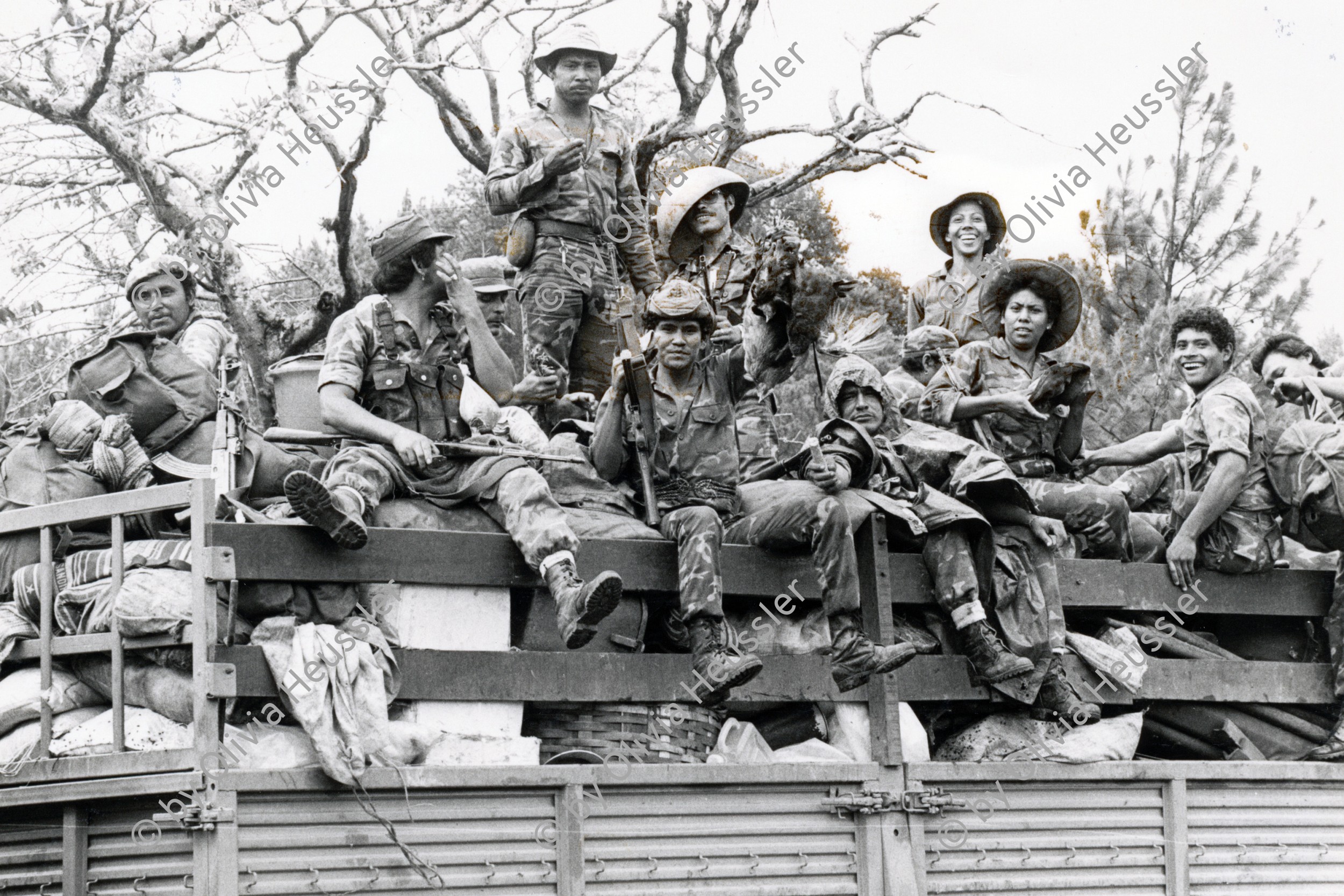 Image of sheet 19850310 photo 20: Der Tag der Demobilisierung des Frauenbataillons Veronica Lacayo nähert sich. Schon sind einige der Soldaten und Soldatinnen von der Front ins Basislager zurückgekommen. Sie sind ausgelaugt müde und glücklich.  Die Lastwagen werden gefüllt und ab gehts nach Hause, nach Leon, nach 9 Monaten Front Krieg in den Bergen. Frauenbataillon Veronica Lacayo, 
Leon Nicaragua 1985 √
The Sandinista Popular Army (or People's Army; Ejército Popular Sandinista, EPS) was the military established in 1979 by the new Sandinista government to replace the National Guard, following the overthow of Anastasio Somoza Debayle.

AK-47 Awtomat Kalaschnikowa, obrasza 47 (kyrillisch Автомат Калашникова образца 47), ein sowjetisch-russisches Sturmgewehr.
Aus: «Der Traum von Solentiname/The dream of Solentiname/El sueño de Solentiname»
Army Military EPS Ejército Popular Sandinista Soldier War Krieg FSLN