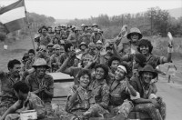 Image of sheet 19850320 photo 41: frtsg. 850310 Die Brücken werden nach Mienen abgesucht. Der Teniente Primero Carlos Morales schaut mir schön in die Camera. Konvoi Militär Die Frauen sandinstisches Bataillon «Veronica Lacayo» reisen übermütig in einem eigenen Lastwagen mitten im Konvoi. Viele schreien fast vor Freude, andere schauen skeptisch an den Berghügeln entlang die Horizonte nach Contras ab. Der Konvoi folgt uns treu. Fahnen werden geschwungen. Die einen steigen aus und tanzen. Freudensmomente am Eingang nach Leon. Wo ist mein Mann, mein Sohn. Die Frauen stehen gespannt am Strassenrand.
Military Army Sandinist Women Soldier
Aus: «Der Traum von Solentiname/The dream of Solentiname/El sueño de Solentiname» Leon Nicaragua 1985
The Sandinista Popular Army (or People's Army; Ejército Popular Sandinista, EPS) was the military established in 1979 by the new Sandinista government to replace the National Guard, following the overthow of Anastasio Somoza Debayle.