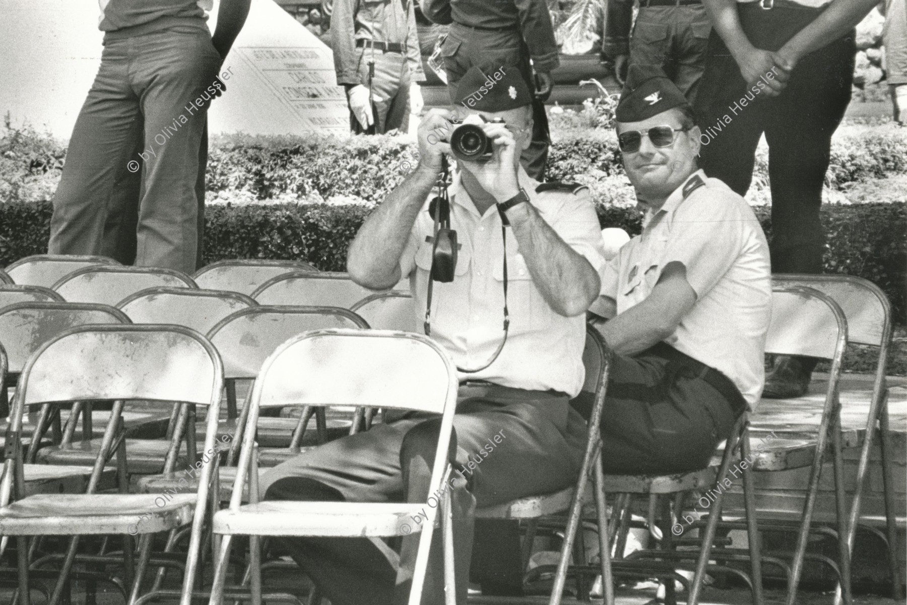 Image of sheet 19850360 photo 11: Zwei US-amerikanische Armeeangehörige und Gäste observieren die anwesenden Journalistinnen, während einer Veranstaltung der sandinistischen Armee. Managua Nicaragua 13.07.85 1985 √
Two members of US-military taking pictures of journalists during celebration of sandinist peoples army.