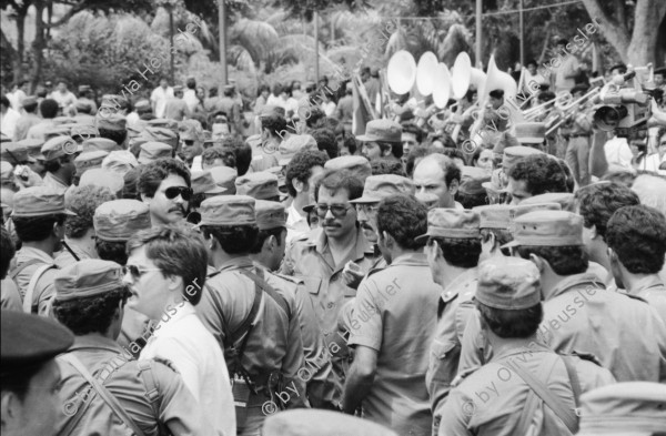 Image of sheet 19850360 photo 16: Auf dem Platz vor dem National Palast Plaza de la Revolution, stehen tausende von sandinistischen Soldaten sandinistischer sandinisten EPS bereit für ein Abtreten. demobilisation. Humberto Ortega spricht an sie. US Amerikanische Militäroffiziere fotografieren uns  Journalisten Das Monument für die Bauern Campesinos mit der Kalaschnikov AK 47  in Managua wird bald der Oeffentlichkeit übergeben und vom Gerüst befreit. 
'Nuestra descision de patria libre o morir no es una simple promesa'. Carlos Fonseca.Unsere Entscheidung ob Freies Vaterland oder Tod ist nicht nur eine einfache Voraussagung. einfaches Versprechen. Sechs Jahre Revolution. Das siegreiche Nicaragua verkauft und ergibt sich nicht! Militärparade Managua Nicaragua 1985