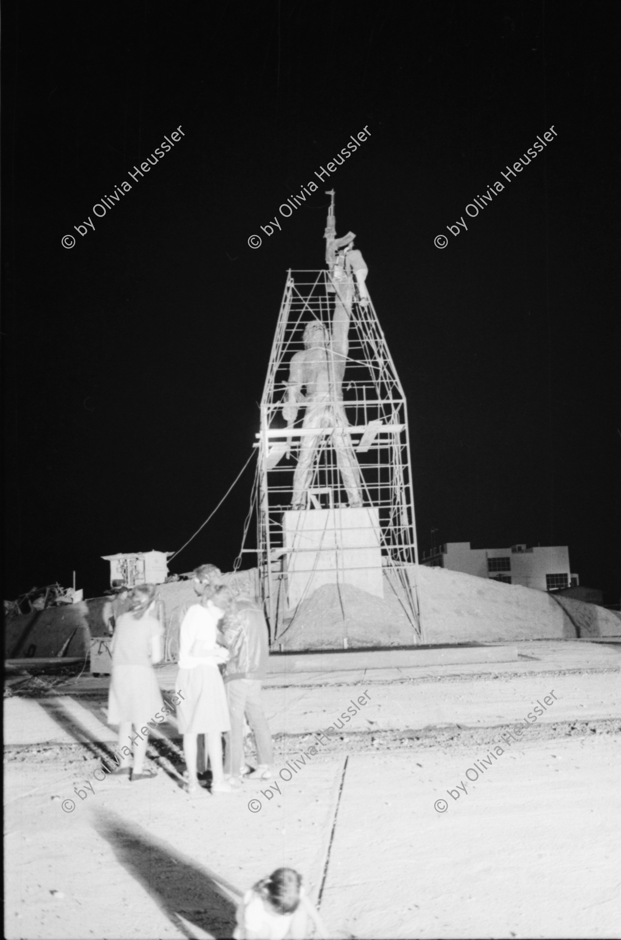 Image of sheet 19850360 photo 27: Auf dem Platz vor dem National Palast Plaza de la Revolution, stehen tausende von sandinistischen Soldaten sandinistischer sandinisten EPS bereit für ein Abtreten. demobilisation. Humberto Ortega spricht an sie. US Amerikanische Militäroffiziere fotografieren uns  Journalisten Das Monument für die Bauern Campesinos mit der Kalaschnikov AK 47  in Managua wird bald der Oeffentlichkeit übergeben und vom Gerüst befreit. 
'Nuestra descision de patria libre o morir no es una simple promesa'. Carlos Fonseca.Unsere Entscheidung ob Freies Vaterland oder Tod ist nicht nur eine einfache Voraussagung. einfaches Versprechen. Sechs Jahre Revolution. Das siegreiche Nicaragua verkauft und ergibt sich nicht! Militärparade Managua Nicaragua 1985