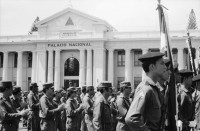 Image of sheet 19850360 photo 7: Auf dem Platz vor dem National Palast Plaza de la Revolution, stehen tausende von sandinistischen Soldaten sandinistischer sandinisten EPS bereit für ein Abtreten. demobilisation. Humberto Ortega spricht an sie. US Amerikanische Militäroffiziere fotografieren uns  Journalisten Das Monument für die Bauern Campesinos mit der Kalaschnikov AK 47  in Managua wird bald der Oeffentlichkeit übergeben und vom Gerüst befreit. 
'Nuestra descision de patria libre o morir no es una simple promesa'. Carlos Fonseca.Unsere Entscheidung ob Freies Vaterland oder Tod ist nicht nur eine einfache Voraussagung. einfaches Versprechen. Sechs Jahre Revolution. Das siegreiche Nicaragua verkauft und ergibt sich nicht! Militärparade Managua Nicaragua 1985