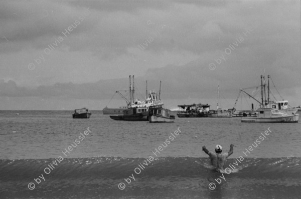 Image of sheet 19850370 photo 39: frtsg. 850350 Hungerstreik von Miguel D'Escoto. Ein junger Mann bepinselt sein Haus mit weisser Farbe. Auf seinem Rücken trägt er die Farben Rot und Schwarz. Sie sind die Propagandafarben für die Sandinisten zu den Wahlen. Die Schwester von Michel Hüttner. In San Juan del Sur fotografiere ich Pelikane die ihren Jungen über dem Meer beim Jagen helfen. San Juan del Sur Nicaragua 1985