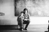 Image of sheet 19850420 photo 33: Ich bin mit Nadine Hostettler unterwegs für eine Reportage über Kunst im Krieg für die Basler Zeitung. Wir sprechen mit Bayardo Gamez ein Künstler aus Esteli er arbeitet mit Juanita Brüssel zusammen. Sein Atelier ist voller Tierschädel behenkt. Die Eingangshalle im Haus wo seine Mutter Maria einen Laden betreibt, ist mit alten Postern aus der Zeit um s 68 dekoriert, seine Grossmutter stirbt am nächsten Tag. Ich mache ihr letztes Bild. Miguel Romero zeigt sein Bild 'We are the World' in Somoto. Die Kirche von Somoto. Unter dem Baum stehen Maulesel. 
nr. 31 Miguel Obando in Somoto mit seiner Mutter Ein abgestürztes Flugzeug liegt im Friedhof Wrack bei Condega.  Che Guevara hängt fast in jeder Küche. Ein Comics zeichner mit seinem Kind auf den Knien. Silla Stuhl Nicaragua 1985