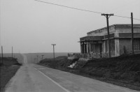 Image of sheet 19850440 photo 10: Am frühen Morgen fahre ich nach El Crucero . Es liegt hoch über Managua und es liegt immer im Nebel des Schwefeldampfes vom Vulkan Masaya. es ist ein paar Grade kühler dort. Der Schwefeldampf vom Vulkan in  Masaya, dem Santiago macht es der Natur unmöglich zu gedeihen. Bäume und andere Pflanzen ertragen
diese Luft nicht. Trotzdem stehen da einige Häuser und vereinzelt sehe ich Menschen. Frau mit Rind Kinder stehen da. Ein Mädchen vor einer Bretterwand Haus. Wandmalereien. COSEP Leute an PK.
José Chepe auf Motorrad Trautes. Gruppenbild Carretera sur. Managua 1985