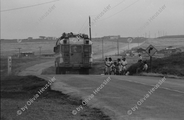 Image of sheet 19850440 photo 12: Am frühen Morgen fahre ich nach El Crucero . Es liegt hoch über Managua und es liegt immer im Nebel des Schwefeldampfes vom Vulkan Masaya. es ist ein paar Grade kühler dort. Der Schwefeldampf vom Vulkan in  Masaya, dem Santiago macht es der Natur unmöglich zu gedeihen. Bäume und andere Pflanzen ertragen
diese Luft nicht. Trotzdem stehen da einige Häuser und vereinzelt sehe ich Menschen. Frau mit Rind Kinder stehen da. Ein Mädchen vor einer Bretterwand Haus. Wandmalereien. COSEP Leute an PK.
José Chepe auf Motorrad Trautes. Gruppenbild Carretera sur. Managua 1985