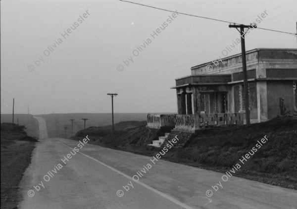 Image of sheet 19850440 photo 13: Am frühen Morgen fahre ich nach El Crucero . Es liegt hoch über Managua und es liegt immer im Nebel des Schwefeldampfes vom Vulkan Masaya. es ist ein paar Grade kühler dort. Der Schwefeldampf vom Vulkan in  Masaya, dem Santiago macht es der Natur unmöglich zu gedeihen. Bäume und andere Pflanzen ertragen
diese Luft nicht. Trotzdem stehen da einige Häuser und vereinzelt sehe ich Menschen. Frau mit Rind Kinder stehen da. Ein Mädchen vor einer Bretterwand Haus. Wandmalereien. COSEP Leute an PK.
José Chepe auf Motorrad Trautes. Gruppenbild Carretera sur. Managua 1985