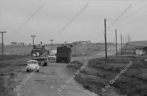 Image of sheet 19850440 photo 22: Am frühen Morgen fahre ich nach El Crucero . Es liegt hoch über Managua und es liegt immer im Nebel des Schwefeldampfes vom Vulkan Masaya. es ist ein paar Grade kühler dort. Der Schwefeldampf vom Vulkan in  Masaya, dem Santiago macht es der Natur unmöglich zu gedeihen. Bäume und andere Pflanzen ertragen
diese Luft nicht. Trotzdem stehen da einige Häuser und vereinzelt sehe ich Menschen. Frau mit Rind Kinder stehen da. Ein Mädchen vor einer Bretterwand Haus. Wandmalereien. COSEP Leute an PK.
José Chepe auf Motorrad Trautes. Gruppenbild Carretera sur. Managua 1985