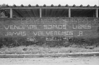Image of sheet 19850440 photo 29: Am frühen Morgen fahre ich nach El Crucero . Es liegt hoch über Managua und es liegt immer im Nebel des Schwefeldampfes vom Vulkan Masaya. es ist ein paar Grade kühler dort. Der Schwefeldampf vom Vulkan in  Masaya, dem Santiago macht es der Natur unmöglich zu gedeihen. Bäume und andere Pflanzen ertragen
diese Luft nicht. Trotzdem stehen da einige Häuser und vereinzelt sehe ich Menschen. Frau mit Rind Kinder stehen da. Ein Mädchen vor einer Bretterwand Haus. Wandmalereien. COSEP Leute an PK.
José Chepe auf Motorrad Trautes. Gruppenbild Carretera sur. Managua 1985