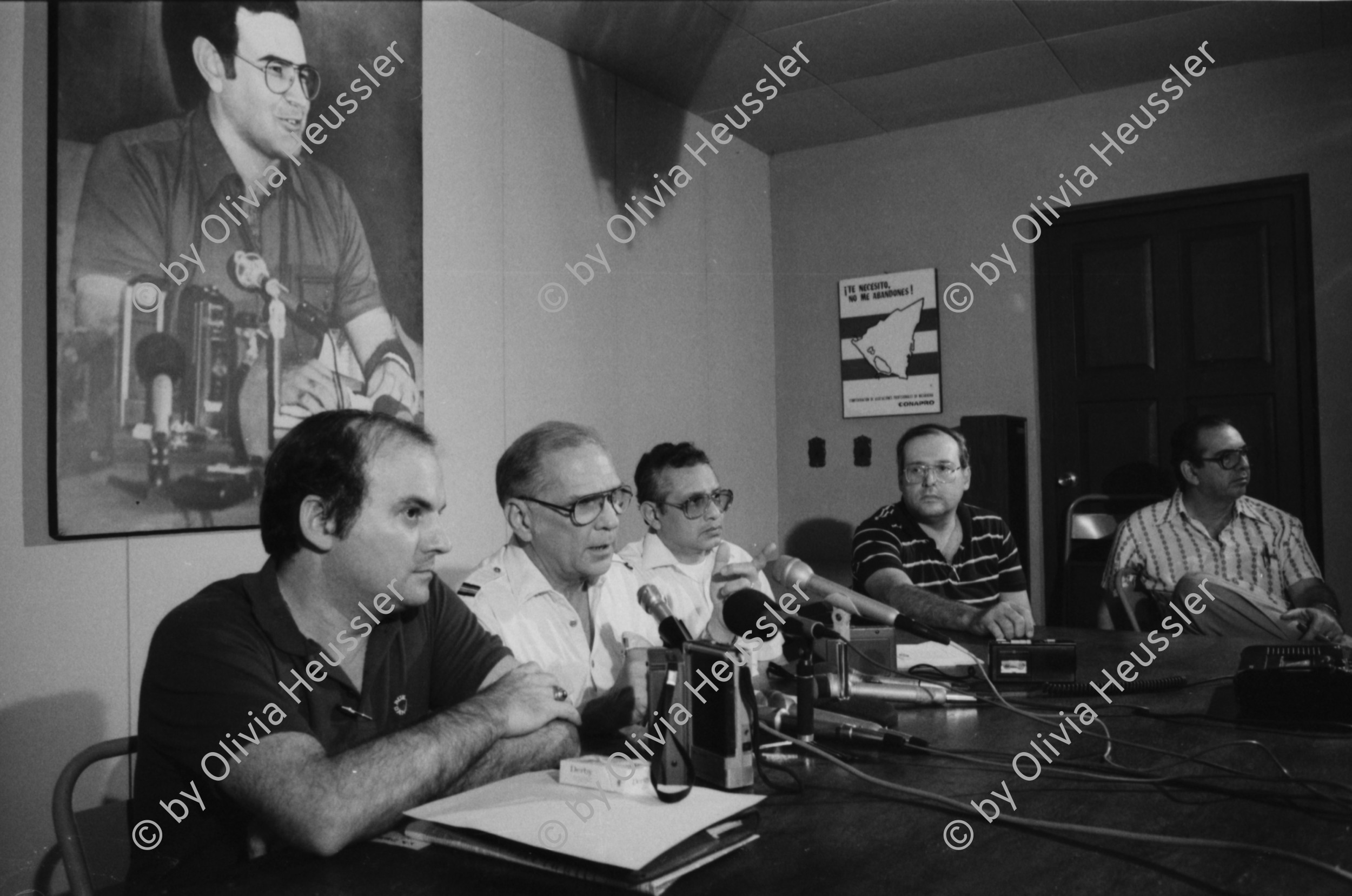Image of sheet 19850440 photo 36: Am frühen Morgen fahre ich nach El Crucero . Es liegt hoch über Managua und es liegt immer im Nebel des Schwefeldampfes vom Vulkan Masaya. es ist ein paar Grade kühler dort. Der Schwefeldampf vom Vulkan in  Masaya, dem Santiago macht es der Natur unmöglich zu gedeihen. Bäume und andere Pflanzen ertragen
diese Luft nicht. Trotzdem stehen da einige Häuser und vereinzelt sehe ich Menschen. Frau mit Rind Kinder stehen da. Ein Mädchen vor einer Bretterwand Haus. Wandmalereien. COSEP Leute an PK.
José Chepe auf Motorrad Trautes. Gruppenbild Carretera sur. Managua 1985