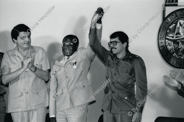 Image of sheet 19850460 photo 34: Aus: Der Traum von Solentiname / The dream of Solentiname / El sueño de 
Präsident Zimbabwes, Robert Mugabe wird von den nicaraguanischen Kommandanten empfangen. re. Daniel Ortega mi. und li. Sergio Ramirez.
Centro de Convenciones 'Olaf Palme'
Managua Nicaragua 1985 

Sergio Ramírez, Robert Mugabe (President of Zimbabwe), and Daniel Ortega (l. to r.) Olof Palme Convention Center, Managua, 1985