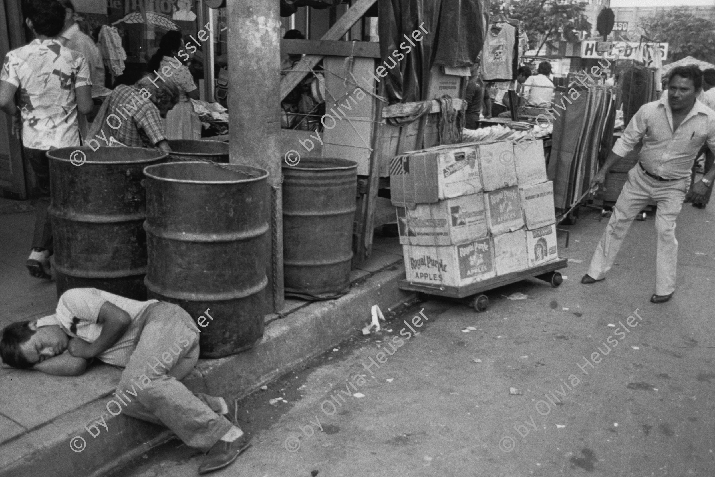 Image of sheet 19850471 photo 7: Ein Mann schläft auf dem Trottoir in der Innenstadt. Ware auf einem Gehsteig. 
Zentralamerika Centralamerica El Salvador 1985 √ man drunk sleeping on the sidewalk work
© 1985, OLIVIA HEUSSLER / www.clic.li