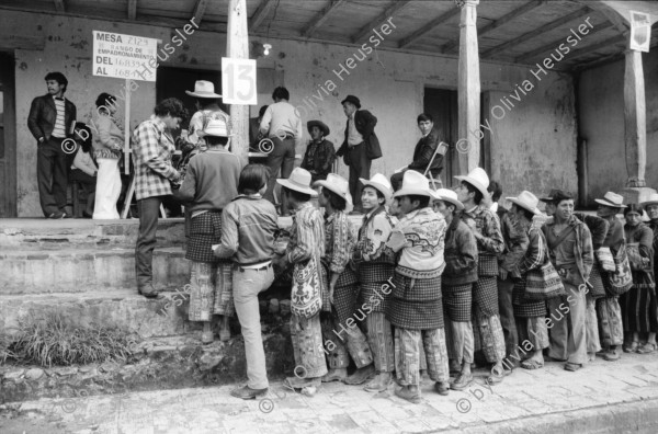 Image of sheet 19850520 photo 14: frtsg. 850510 Feier in Santiago de Atitlan. In Panachajel wählen die IndianerInen ihr den Präsidenten. Jan Schmeitz holländischer Fernseh TV Journalist an der Schreibmaschiene vor dem Hotel. Portrait. Die Bauern in ihren jeweiligen Trachten stehen vor dem Wahllokal in der Schlange. Gruppenbild Wahlen. Eine Mutter Campesina Indigena Indio und ihr Kind im Tuch wählt. In Solola ist der Platz voll von Menschenschlangen die den neuen Präsidenten wählen müsssen. Die Autodefensa ist ein gefährlicher Kontrollmechansimus zur Ueberwachung der eigenen Dorfwache Dorfwächter Dorfbevölkerung. Sie sind vom Staat organisiert und tragen auch einfache Holzgewehratrappen. Zwei alte Bauern in Patzun. Bauern beim wählen. Campesinos Guatemala 1985