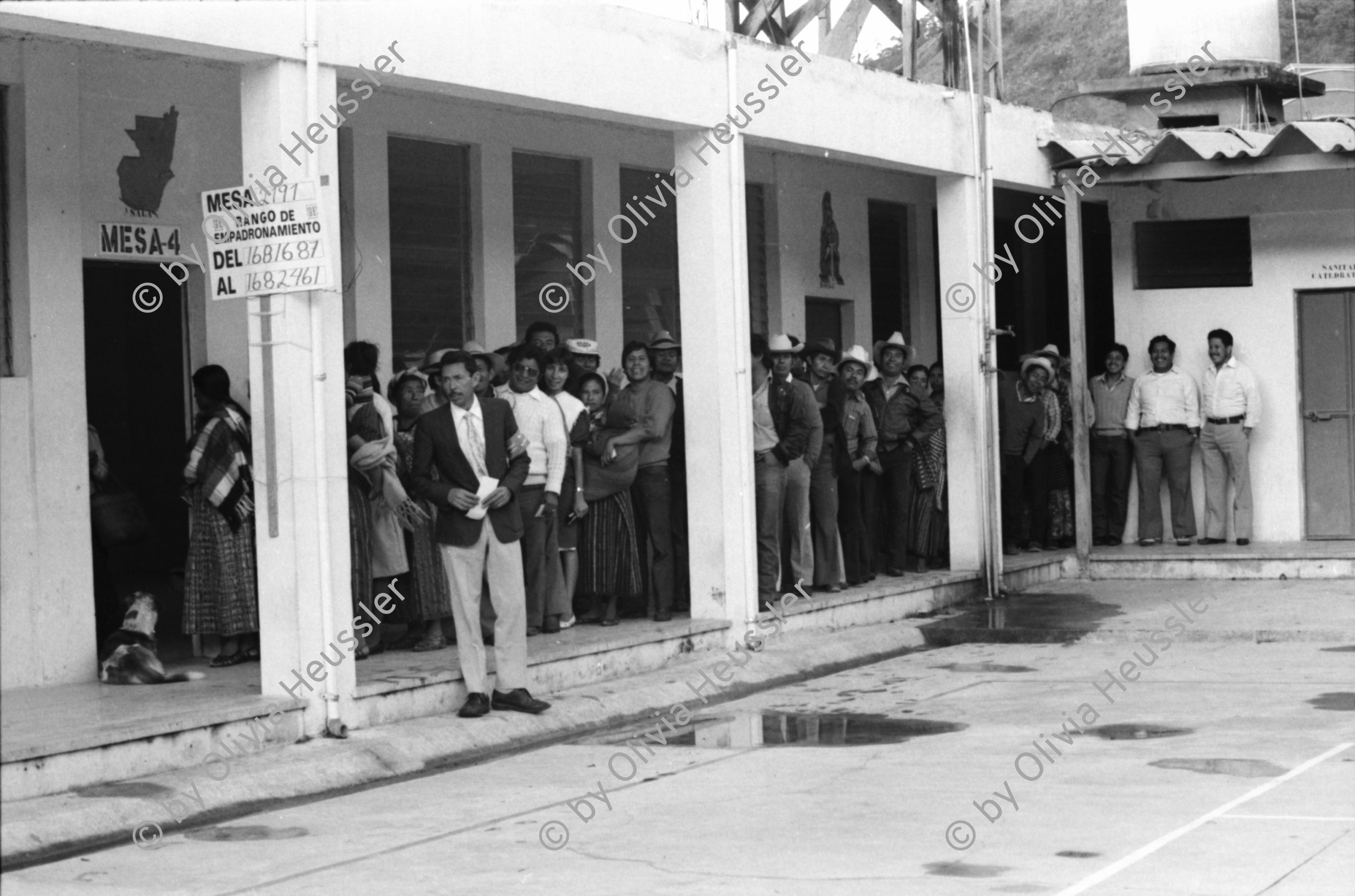 Image of sheet 19850520 photo 6: frtsg. 850510 Feier in Santiago de Atitlan. In Panachajel wählen die IndianerInen ihr den Präsidenten. Jan Schmeitz holländischer Fernseh TV Journalist an der Schreibmaschiene vor dem Hotel. Portrait. Die Bauern in ihren jeweiligen Trachten stehen vor dem Wahllokal in der Schlange. Gruppenbild Wahlen. Eine Mutter Campesina Indigena Indio und ihr Kind im Tuch wählt. In Solola ist der Platz voll von Menschenschlangen die den neuen Präsidenten wählen müsssen. Die Autodefensa ist ein gefährlicher Kontrollmechansimus zur Ueberwachung der eigenen Dorfwache Dorfwächter Dorfbevölkerung. Sie sind vom Staat organisiert und tragen auch einfache Holzgewehratrappen. Zwei alte Bauern in Patzun. Bauern beim wählen. Campesinos Guatemala 1985