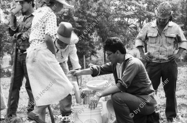 Image of sheet 19860020 photo 14: Film: Mujeres de la Frontera. Direktor Yvan Arguello Lacayo von INCINE. Kamera Rafael Ruiz mein alter Freund. Haupt darstellerin Pauline von Jalapa. Frauen arbeiten mit langen Instrumenten auf dem Feld. Yvan gibt den Schauspieler Innen (Laien) anweisungen. Er schaut durch die Kamera und Rafael steht daneben. Film cinema work art Nicaragua 1986  school Managua