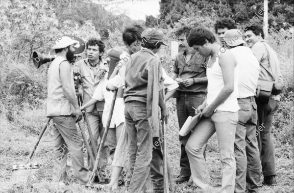 Image of sheet 19860020 photo 20: Film: Mujeres de la Frontera. Direktor Yvan Arguello Lacayo von INCINE. Kamera Rafael Ruiz mein alter Freund. Haupt darstellerin Pauline von Jalapa. Frauen arbeiten mit langen Instrumenten auf dem Feld. Yvan gibt den Schauspieler Innen (Laien) anweisungen. Er schaut durch die Kamera und Rafael steht daneben. Film cinema work art Nicaragua 1986  school Managua