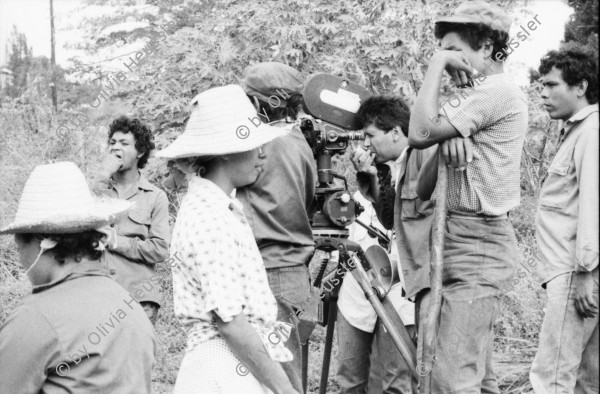 Image of sheet 19860020 photo 28: Film: Mujeres de la Frontera. Direktor Yvan Arguello Lacayo von INCINE. Kamera Rafael Ruiz mein alter Freund. Haupt darstellerin Pauline von Jalapa. Frauen arbeiten mit langen Instrumenten auf dem Feld. Yvan gibt den Schauspieler Innen (Laien) anweisungen. Er schaut durch die Kamera und Rafael steht daneben. Film cinema work art Nicaragua 1986  school Managua