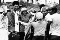 Image of sheet 19860020 photo 7: Film: Mujeres de la Frontera. Direktor Yvan Arguello von INCINE. Haupt darstellerin Pauline von Jalapa. Frauen arbeiten mit langen Instrumenten auf dem Feld. Yvan gibt den Schauspieler Innen (Laien) anweisungen. Auch der Kamera gibt er Anweisungen. Er schaut durch die Kamera und Rafael steht daneben. Film cinema work art Nicaragua 1986  school Managua √ director