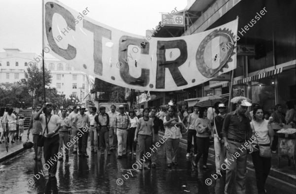 Image of sheet 19860080 photo 11: Transparente Protest Demonstration gegen den Krieg, gegen die Intervention, 1. Mai Demo im Zentrum der Stadt. Mit Musik. Die Kirche hält einen Gottesdienst. Utensilien aus Silber. CTCTR Gewerkschaft. San José de Costa Rica 1986