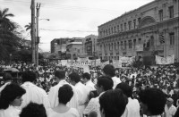 Image of sheet 19860080 photo 13: Transparente Protest Demonstration gegen den Krieg, gegen die Intervention, 1. Mai Demo im Zentrum der Stadt. Mit Musik. Die Kirche hält einen Gottesdienst. Utensilien aus Silber. CTCTR Gewerkschaft. San José de Costa Rica 1986